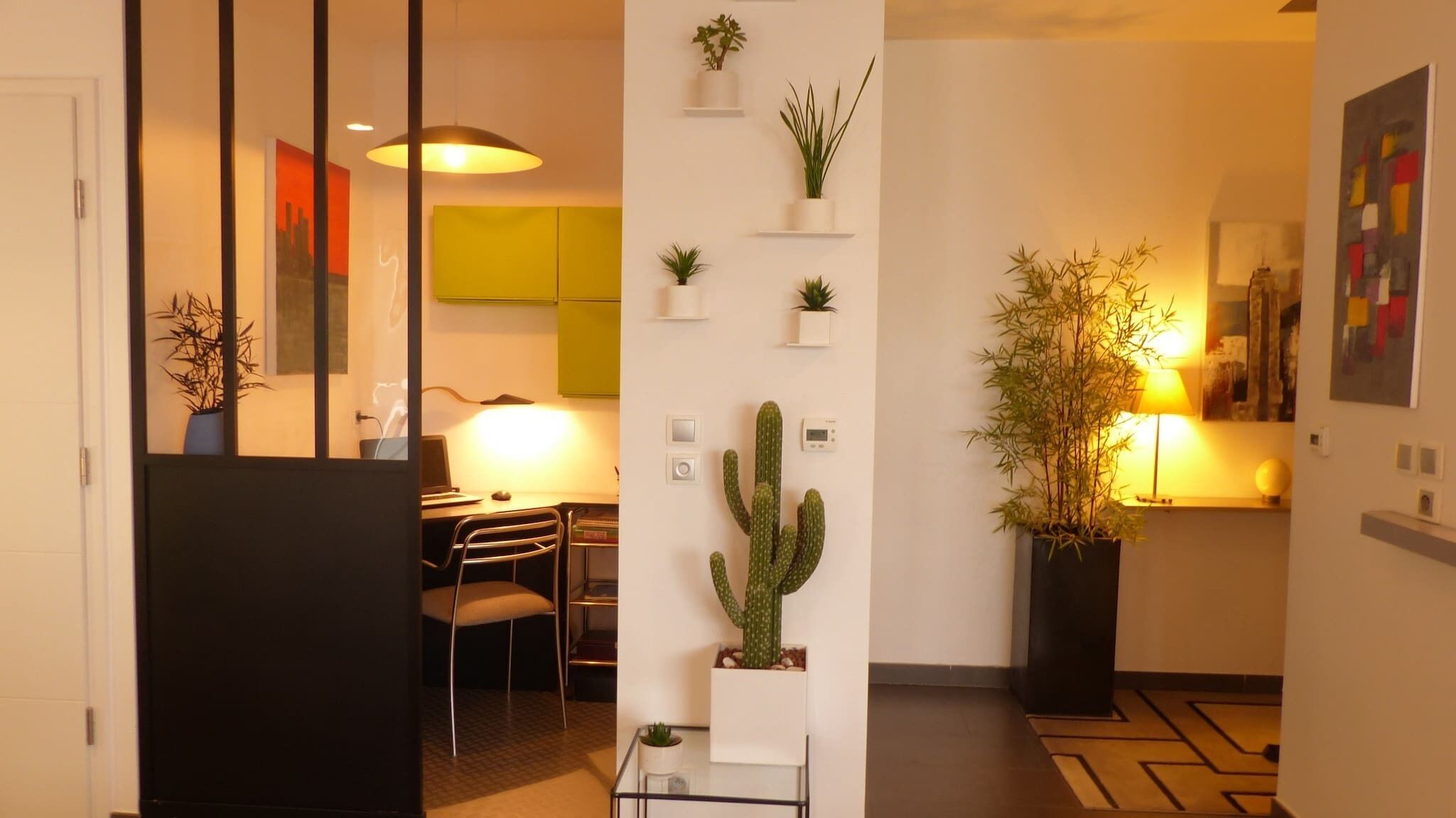 A modern interior with a dining area, a cactus plant, and a lamp.
