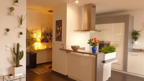 A modern kitchen with white cabinets, a built-in stove, and a central island with a blue vase and flowers. - Vannes, 4-star luxury flat with car park (Vannes)