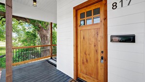 Une porte d’entrée en bois portant le numéro 817, une boîte aux lettres et un porche doté d’une balustrade.