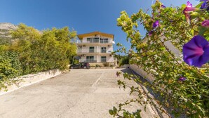 A multi-story building with balconies, a paved driveway, and surrounding greenery. - Stunning 3-bedroom Apartment in Gradac (Gradac)
