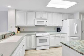 A modern kitchen with white cabinetry, a built-in oven, a microwave, and a refrigerator. - Four Seasons 402-E, Private fishing pier (Orange Beach)