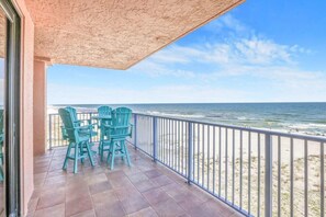 A balcony with a view of the ocean, featuring a table and chairs. - Four Seasons 402-E, Private fishing pier (Orange Beach)