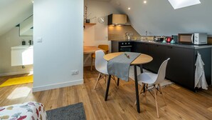 Una cucina compatta con forno a microonde, fornello e lavandino. C'è una zona pranzo con tavolo e sedie.