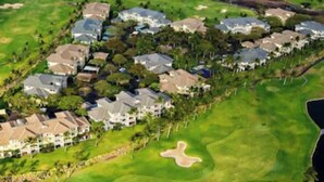 Un terrain de golf doté de bâtiments résidentiels et d’un plan d’eau.