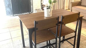 Spiseområde med et træbord, sorte stole, en hvid vase med blomster, et fladskærms-tv monteret på en murstensvæg og en pejs.