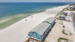 A beachfront property with a large building featuring multiple balconies and a beach in the background.