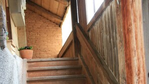 A staircase with wooden steps and a handrail, leading to a brick wall.