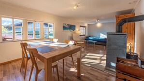 A spacious living area with a wooden dining table, chairs, a sofa, and a fireplace.