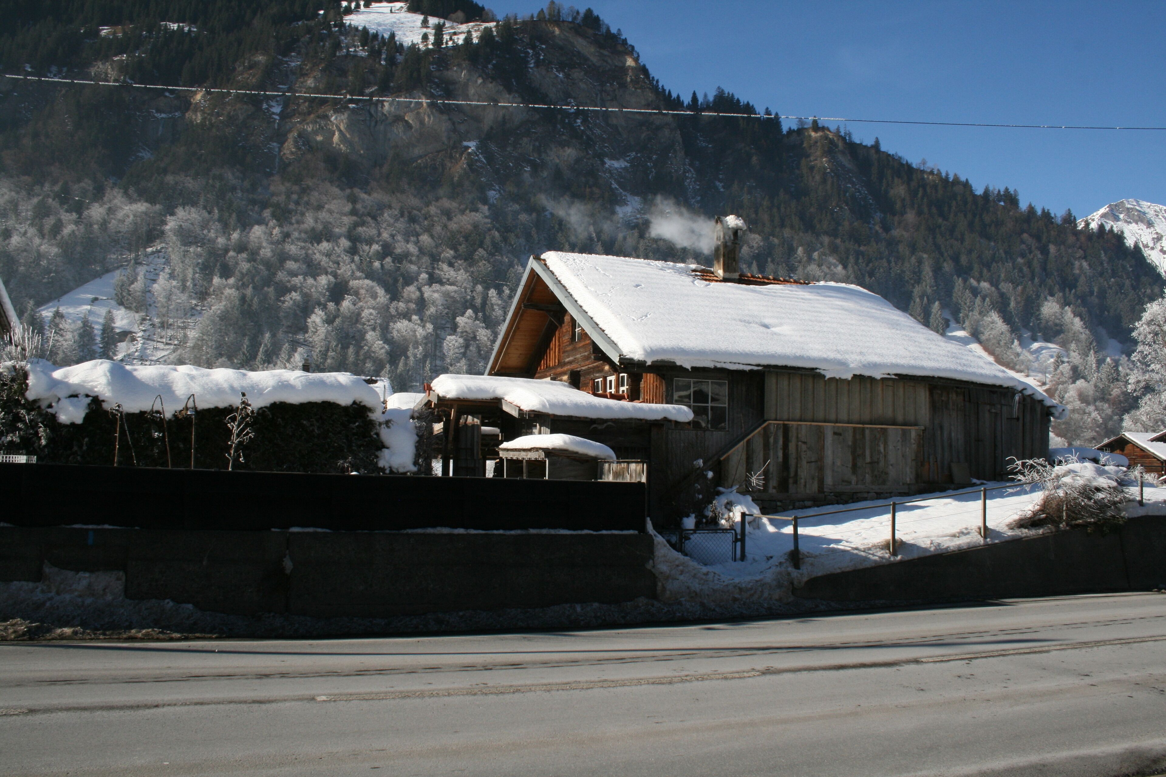 Une cabane en bois, dont le toit est recouvert de neige, nichée au cœur d’un paysage montagneux.