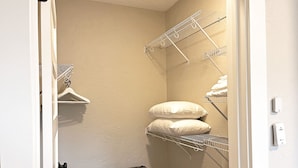 A small, narrow closet with white walls, a metal drying rack, a small stool, and two white pillows. - Historic & Modern! Walk to Restaurants, Moccasin Springs + Huge Suite w/ Kitchen (Hot Springs)