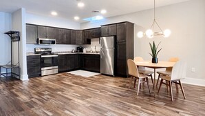 A modern kitchen with dark cabinets, stainless steel appliances, and a dining area with a wooden table and chairs. - Historic & Modern! Walk to Restaurants, Moccasin Springs + Huge Suite w/ Kitchen (Hot Springs)