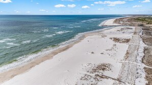 A beach with a clear view of the ocean, sandy shore, and a few people walking. - Golf Cart, Pool, Deck, Grill, & Beach Gear (Mexico Beach)