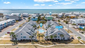 A coastal residential area with a swimming pool, multiple-story buildings, and a view of the ocean. - Golf Cart, Pool, Deck, Grill, & Beach Gear (Mexico Beach)