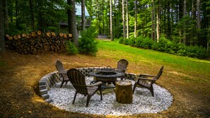 A circular outdoor seating area with chairs and a fire pit, surrounded by a gravel circle. - Perfect Cabin in the Woods! Hot Tub, Fire Pit, WI-FI, Central A/C (Sparta)