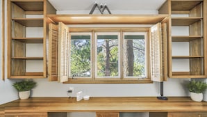 A kitchen with wooden cabinetry, a window with shutters, and a countertop with a sink and a plant. - Colorado Mountain House - Views and a Hot Tub! (Cascade-Chipita Park)