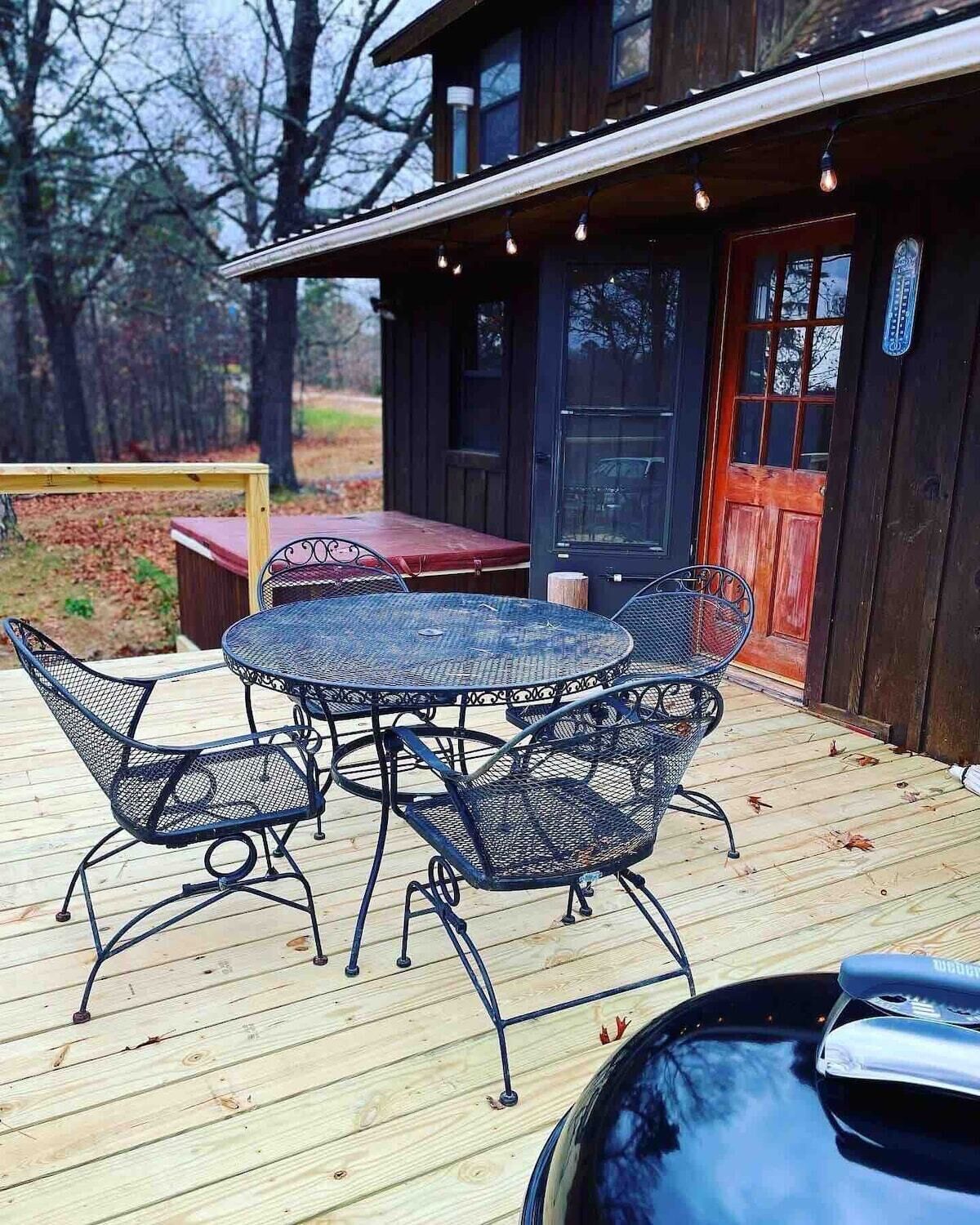 A wooden deck with a round metal table and chairs, a red bench, and a car parked nearby.