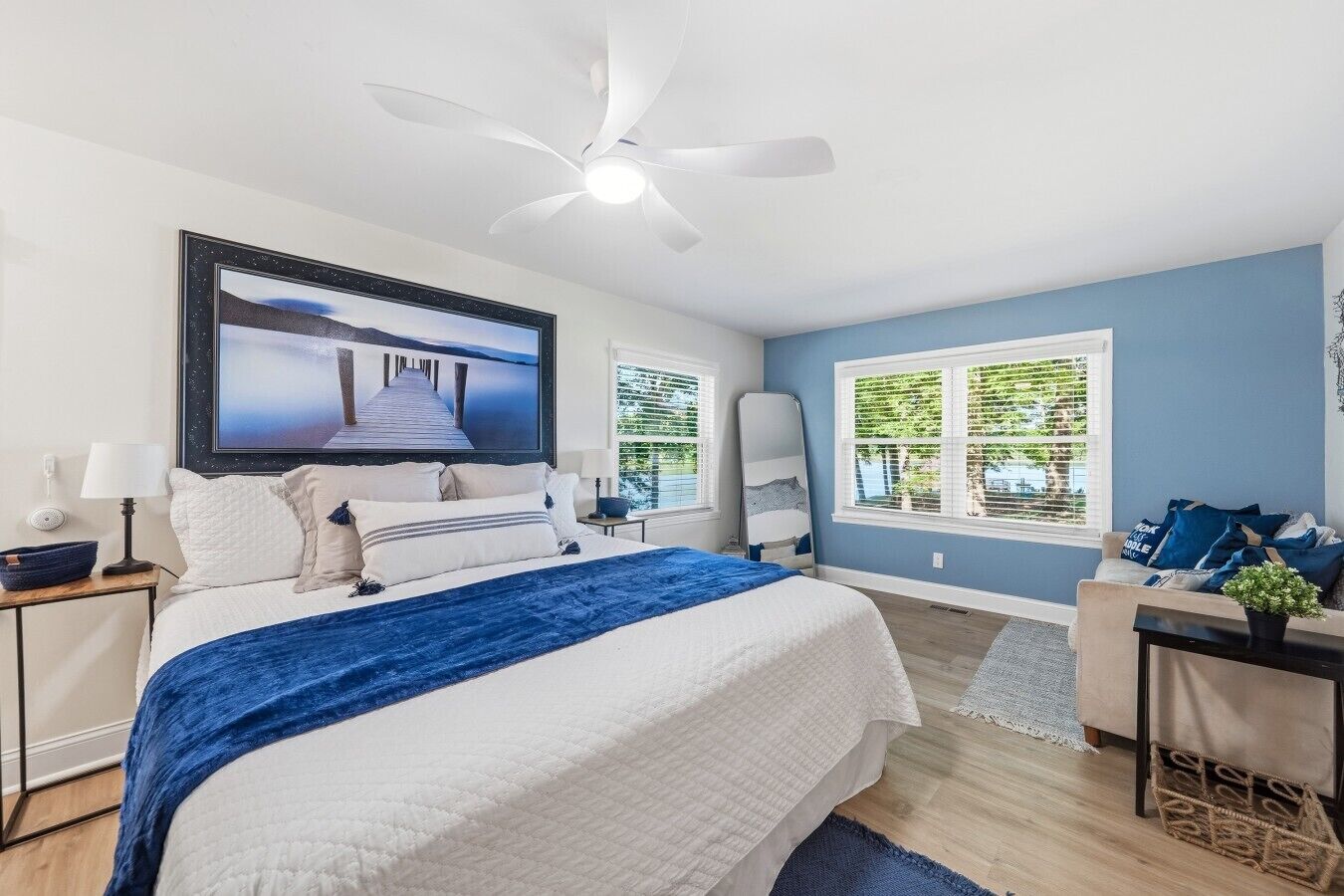 A bedroom with a bed, a ceiling fan, a TV, and a window with blinds.