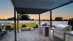 Une terrasse extérieure équipée d’un barbecue, de sièges et d’un foyer.