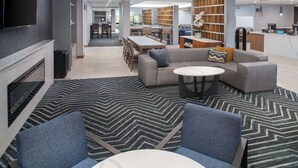 Un hall d’hôtel moderne doté d’une cheminée, d’un espace salon et d’un comptoir d’accueil.