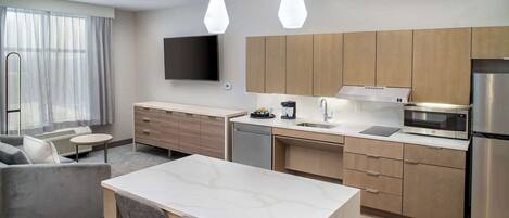 A modern kitchen with a dining area, a flat-screen TV, and a built-in microwave.