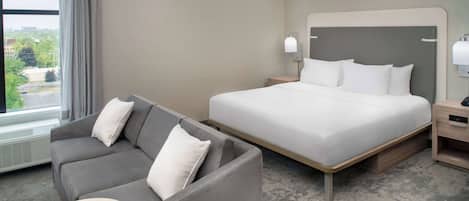 Een hotelkamer met een bed, een slaapbank, een klein tafeltje en een nachtkastje.