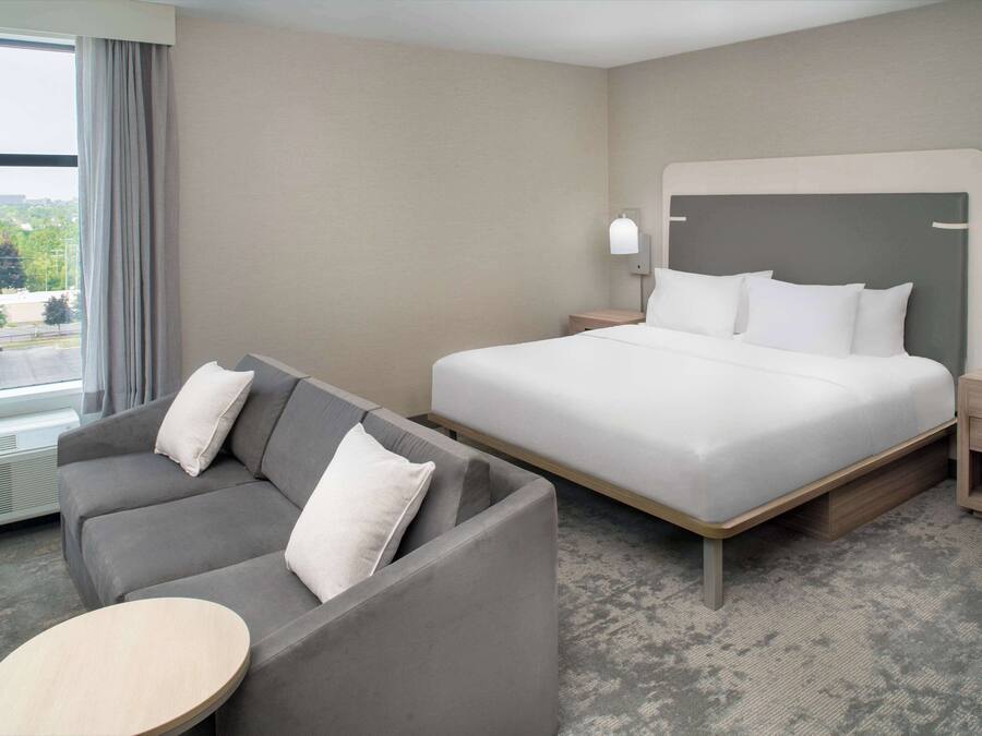 A hotel room with a bed, a sofa, a small table, and a nightstand.