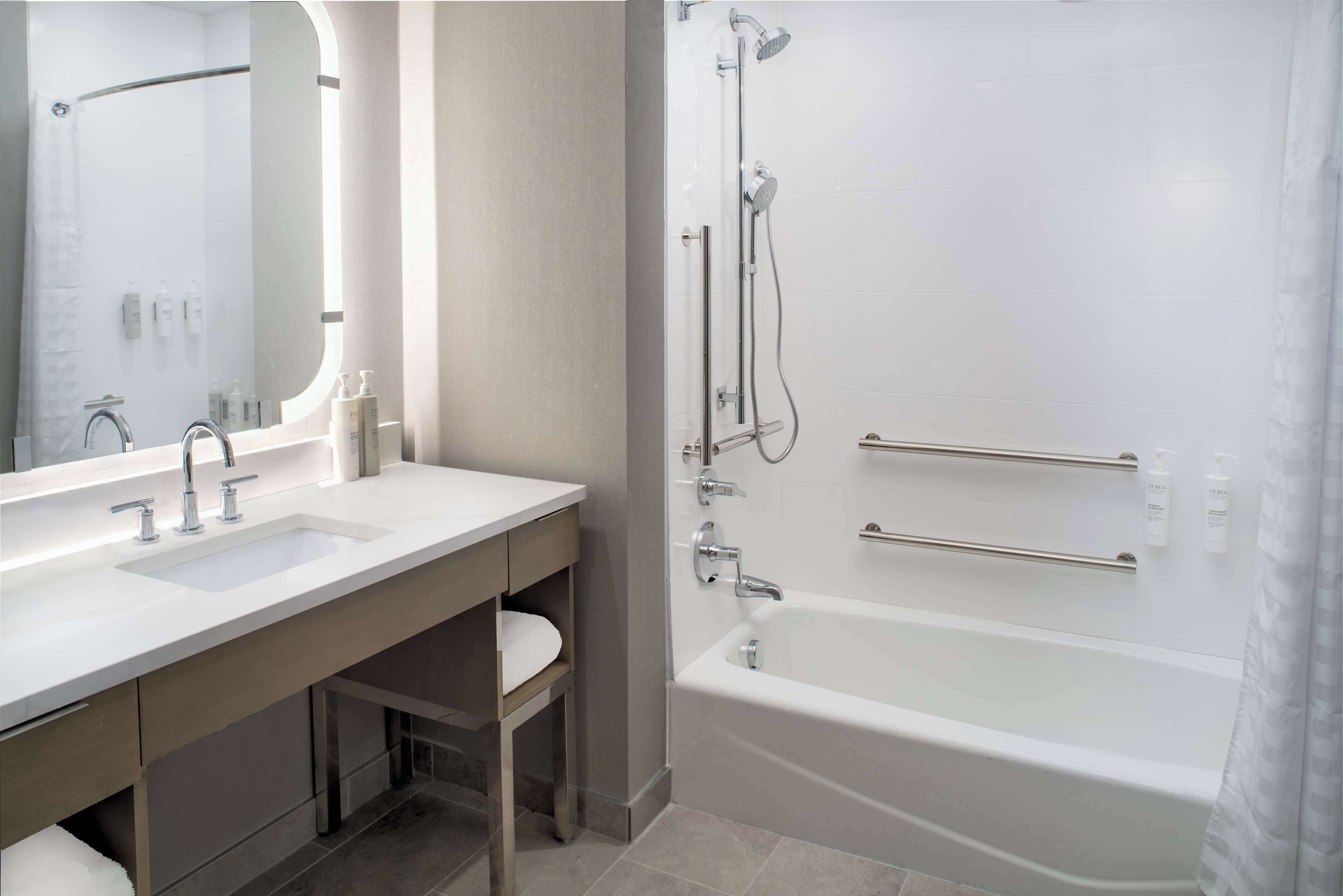 Un baño moderno con dos lavamanos, un espejo grande, una bañera y una ducha.