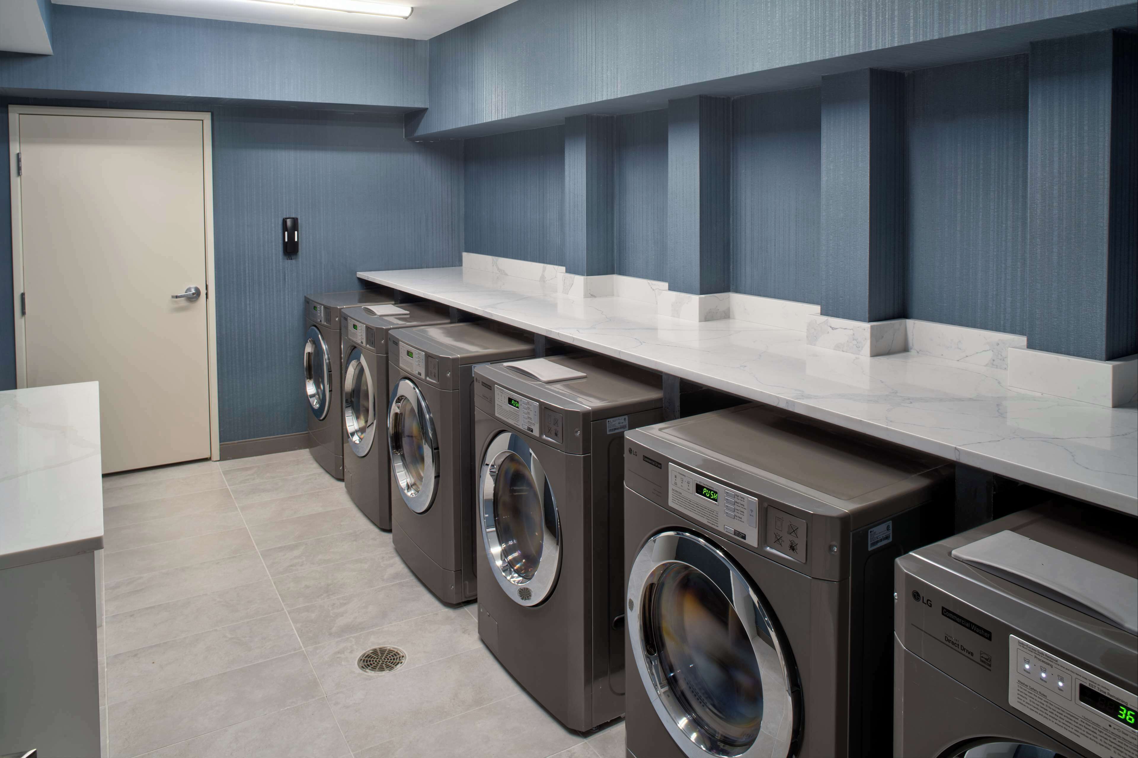 A laundry facility with multiple washing machines and a white countertop.