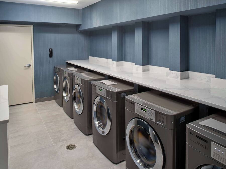 A laundry facility with multiple washing machines and a white countertop.