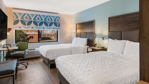 A hotel room with two beds, a desk, a chair, a TV, and a wall with a 'Nail Shop' sign. - Tru by Hilton Greensboro, NC (Greensboro)
