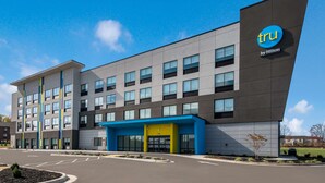 A modern hotel building with a blue and grey facade, a prominent 'tru by Hilton' sign, and a parking lot in front. - Tru by Hilton Greensboro, NC (Greensboro)