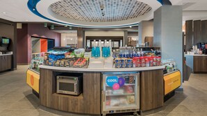 A modern self-service kiosk with a variety of food and beverage options, including snacks, bottled water, and refrigerated items. - Tru by Hilton Greensboro, NC (Greensboro)