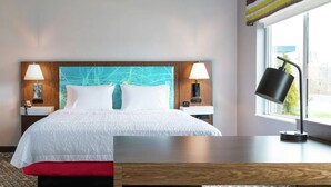 Une chambre d’hôtel avec un lit, des lampes de chevet, une télévision et une fenêtre.