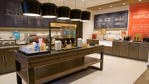 Un comptoir de boulangerie avec des machines à café, un présentoir de produits de boulangerie et une affiche publicitaire pour des gaufres.