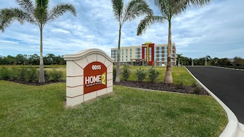 En hotellentréd med en skylt som visar texten ”6015 HOME 2 Suites by Hilton” och en byggnad i bakgrunden.