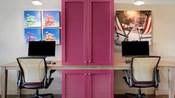 Un espace de travail comprenant deux bureaux, chacun équipé d’un écran d’ordinateur, de deux chaises de bureau et d’un grand meuble rose.