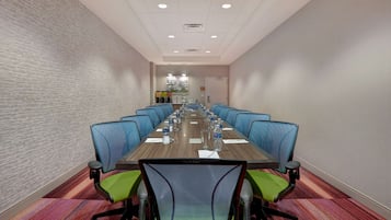 A conference room with a long table, blue chairs, and green chairs.