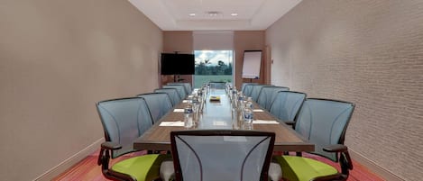 A conference room with a long table, chairs, a projector, and a whiteboard.