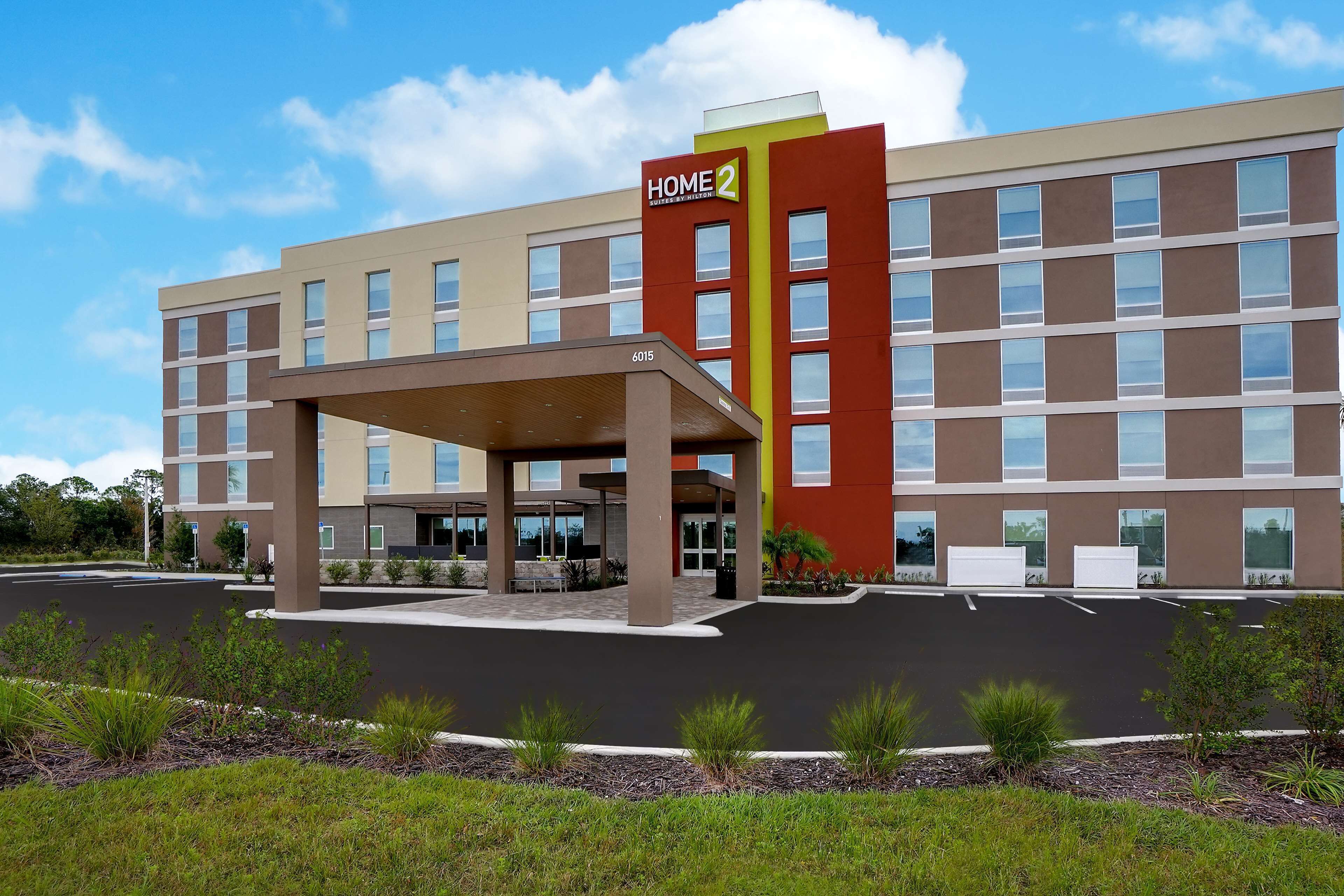 Un hotel moderno con entrada cubierta, varios pisos y un letrero llamativo que dice "Home 2".