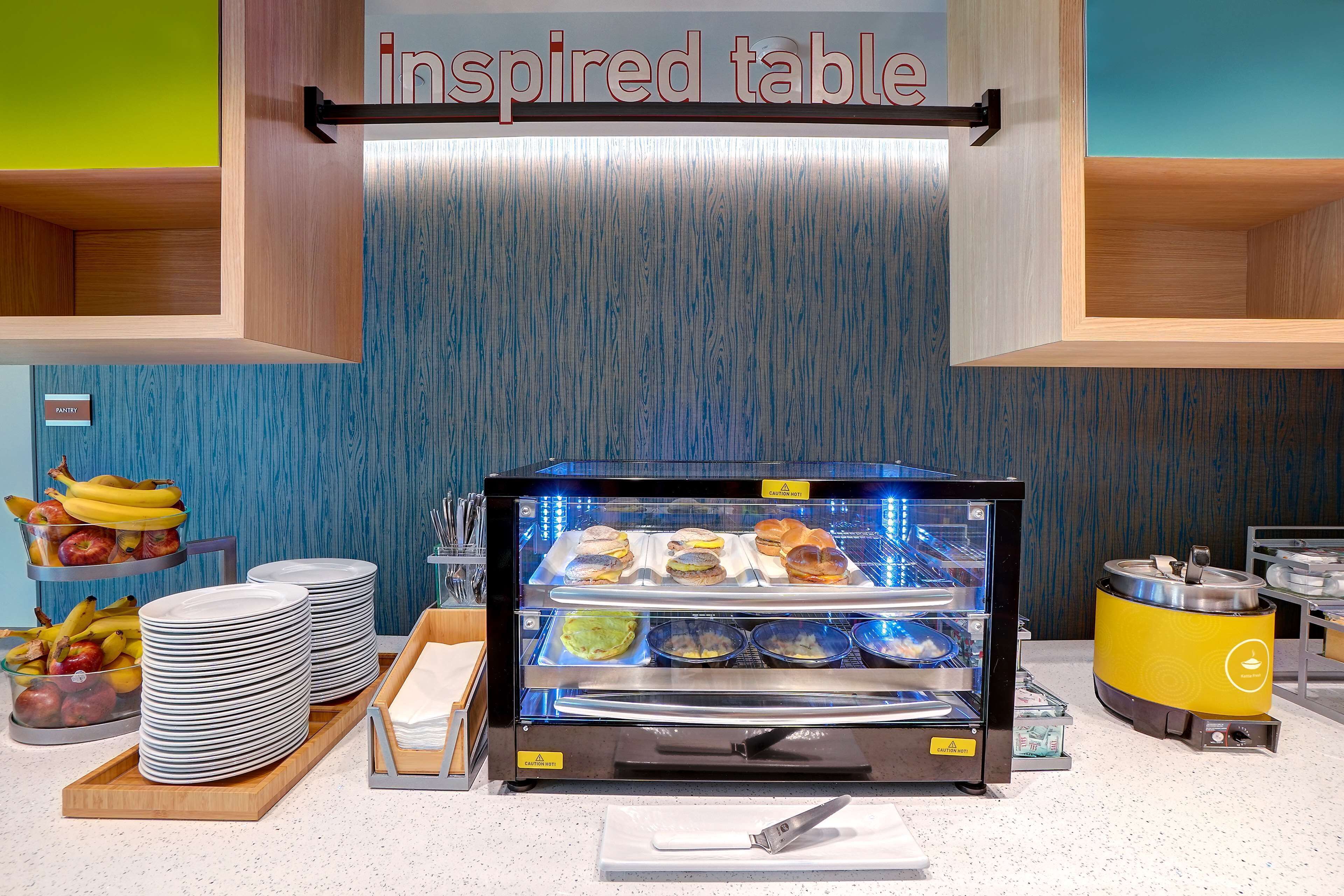 A self-service breakfast station with a variety of food items, plates, and utensils.