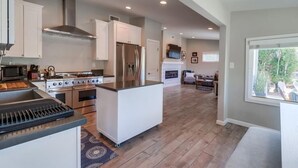 A modern kitchen with a central island, stainless steel appliances, and a dining area with a view. - NEW Super Clean 3 Bed / 2 Bath Home - Fully Loaded (San Diego)