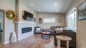 A living room with a fireplace, a sofa, a coffee table, and a TV mounted above the fireplace. - NEW Super Clean 3 Bed / 2 Bath Home - Fully Loaded (San Diego)