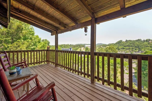 A wooden deck with a railing overlooking a lush green landscape. - Location! Smokies Log Cabin, Hot Tub, Fireplace (Pigeon Forge)