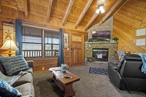 L’intérieur d’un chalet confortable, avec une cheminée, des murs en bois et un manteau de cheminée en pierre.
