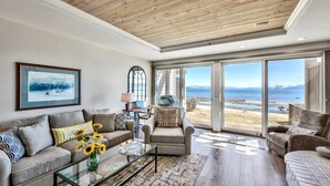 Ein geräumiges Wohnzimmer mit einem großen Fenster und Blick auf Strand und Berge.