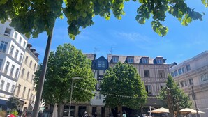 Straßenansicht mit Gebäuden, Bäumen und blauem Himmel.