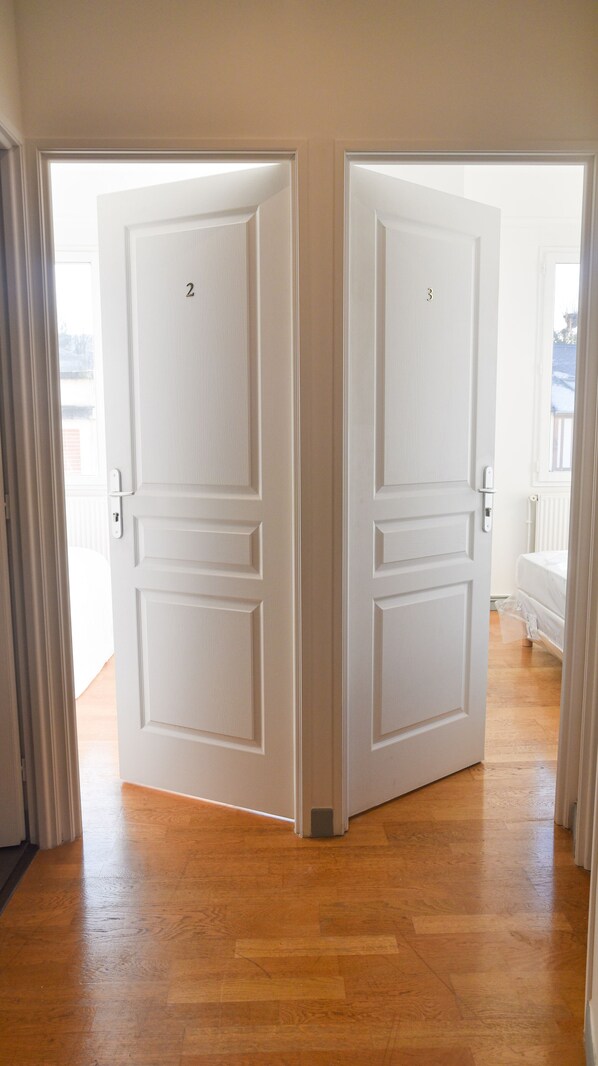 A pair of white double doors with a number '2' on the left door, leading to a room with wooden flooring and a white radiator.