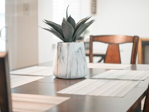 Un vase en marbre orné d’une plante, posé sur une table à manger recouverte de sets de table.