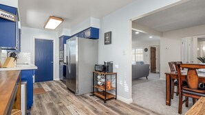Une cuisine moderne avec un réfrigérateur en acier inoxydable, un plancher en bois et des armoires bleues.