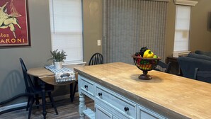 A kitchen with a wooden island, a dining table with chairs, and a fruit bowl.